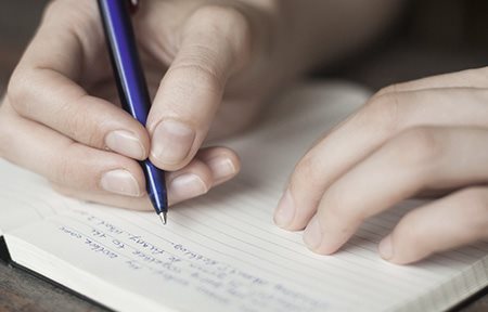 صورة فوتوغرافية لإمرأة تكتب مذكرات يومية عن المحفزات
