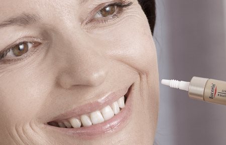 امرأة تضع منتج Eucerin على خدها الأيسر. 