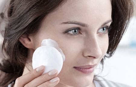 امرأة تنظف وجهها بواسطة قطعة قطنية 