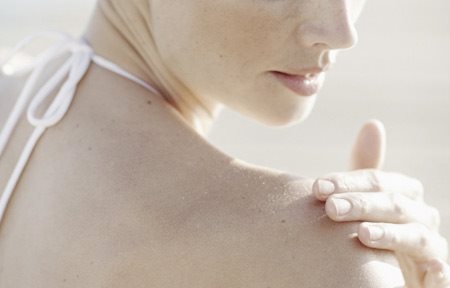 امرأة تضع كريم على كتفها الأيمن